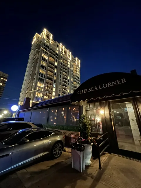 Chelsea Corner exterior at night with classic awning and Dallas skyline