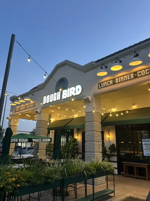 Dough Bird exterior at dusk with illuminated signage and string lights