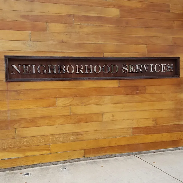 Neighborhood Services exterior signage on warm wood-plank wall