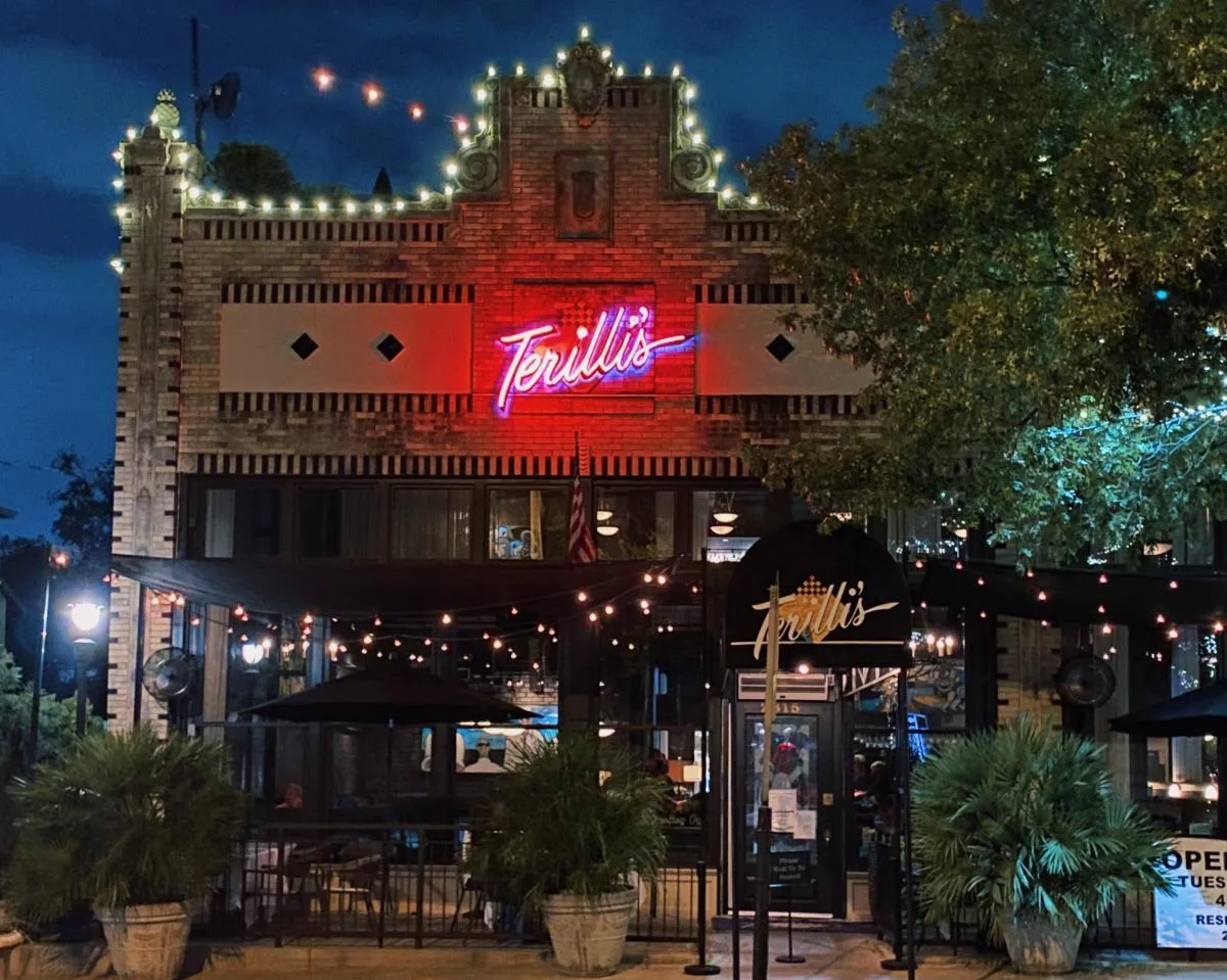 Terilli's exterior at night with red neon sign and string lights on Greenville Avenue